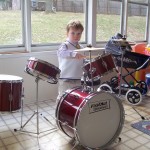 The kid aged 2 banging away at a drumkit.