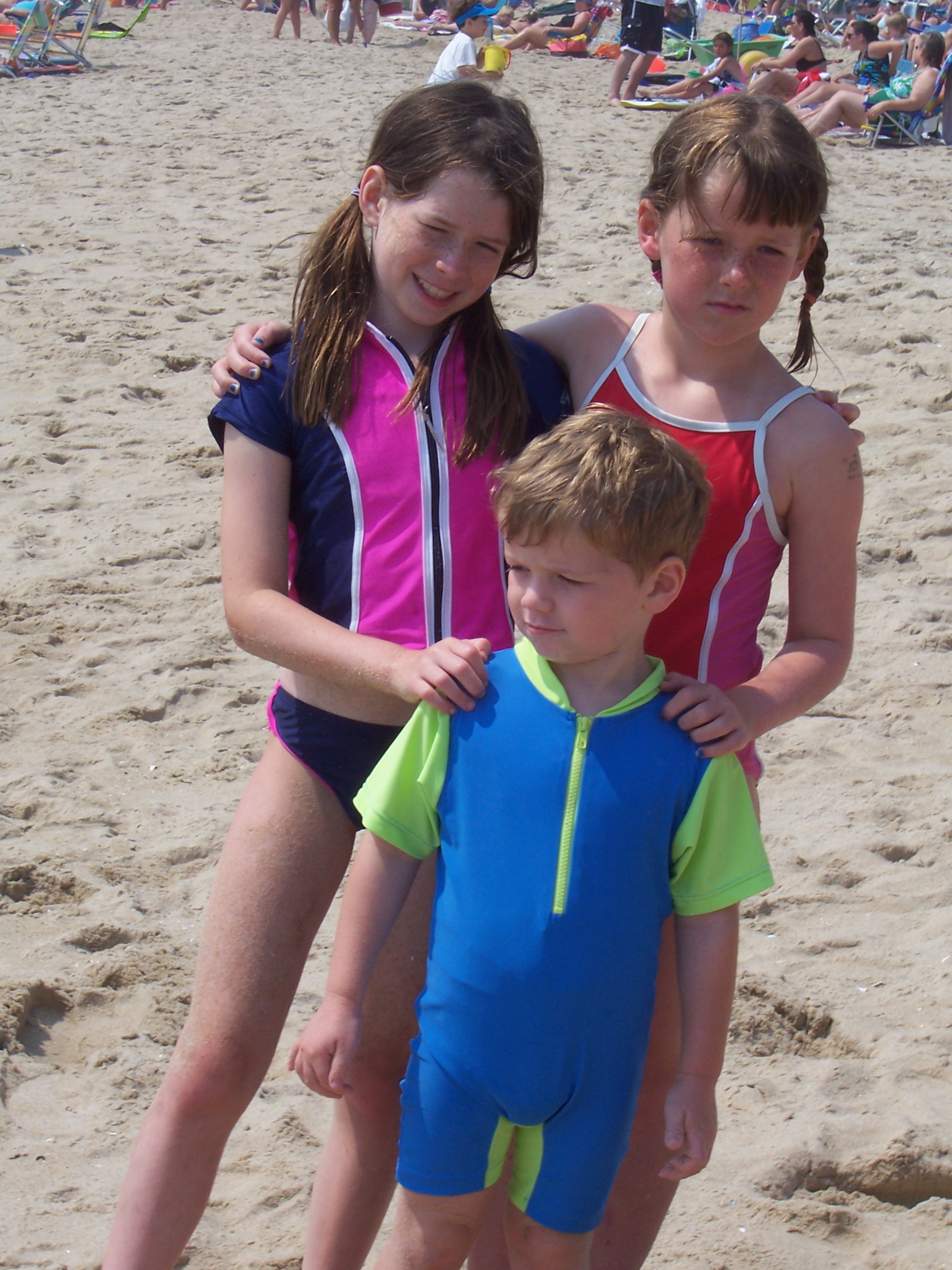 Kids on a beach wearing swimsuits and rashguard shirts