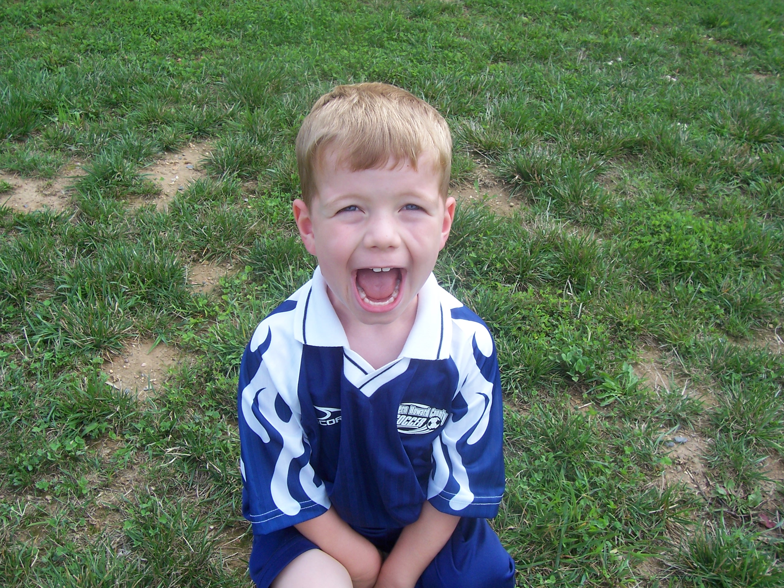 Happy younger sibling on the sideline of big sibling's youth soccer team game! Kid is wearing an old soccer jersey as well! Kid can't wait for his turn to play soccer!